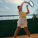 Child playing tennis on a court with a Roggio outfit
