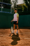 Child holding a tennis racket on a tennis court wearing roggio tennis apparel