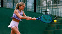 Young girl playing tennis on a court wearing Roggio tennis outfit