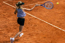 Junior tennis playing tennis on a clay court, swinging a racket towards a ball in Roggio outfit