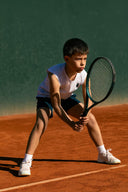 Young boy playing tennis on a clay court in Roggio outfit